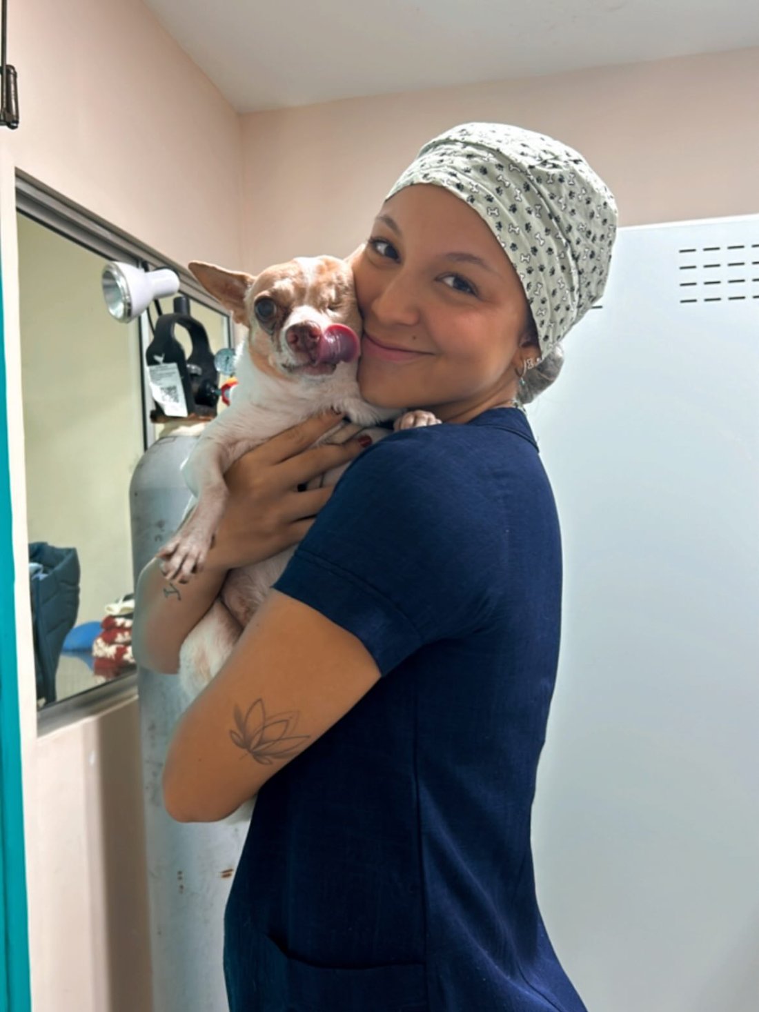 Dra. Clara Viana de jaleco e touca cirúrgica segurando um chihuahua no colo